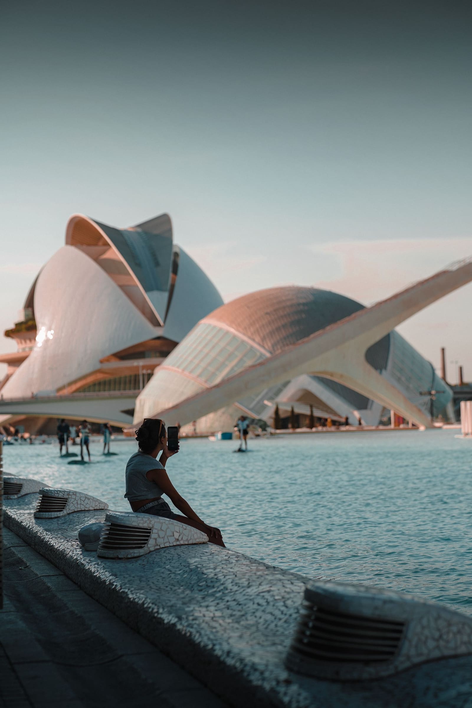 Someone resting by the water in front of the City of Arts and Sciences