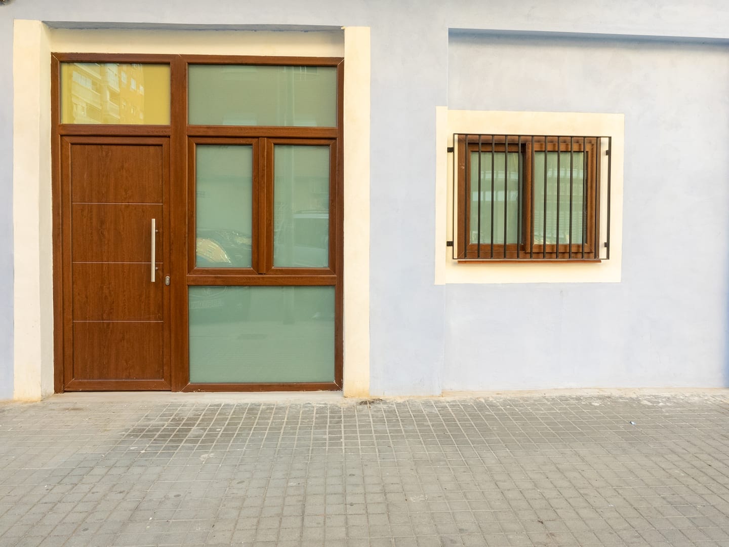 Blue façade with a wooden door and a barred window