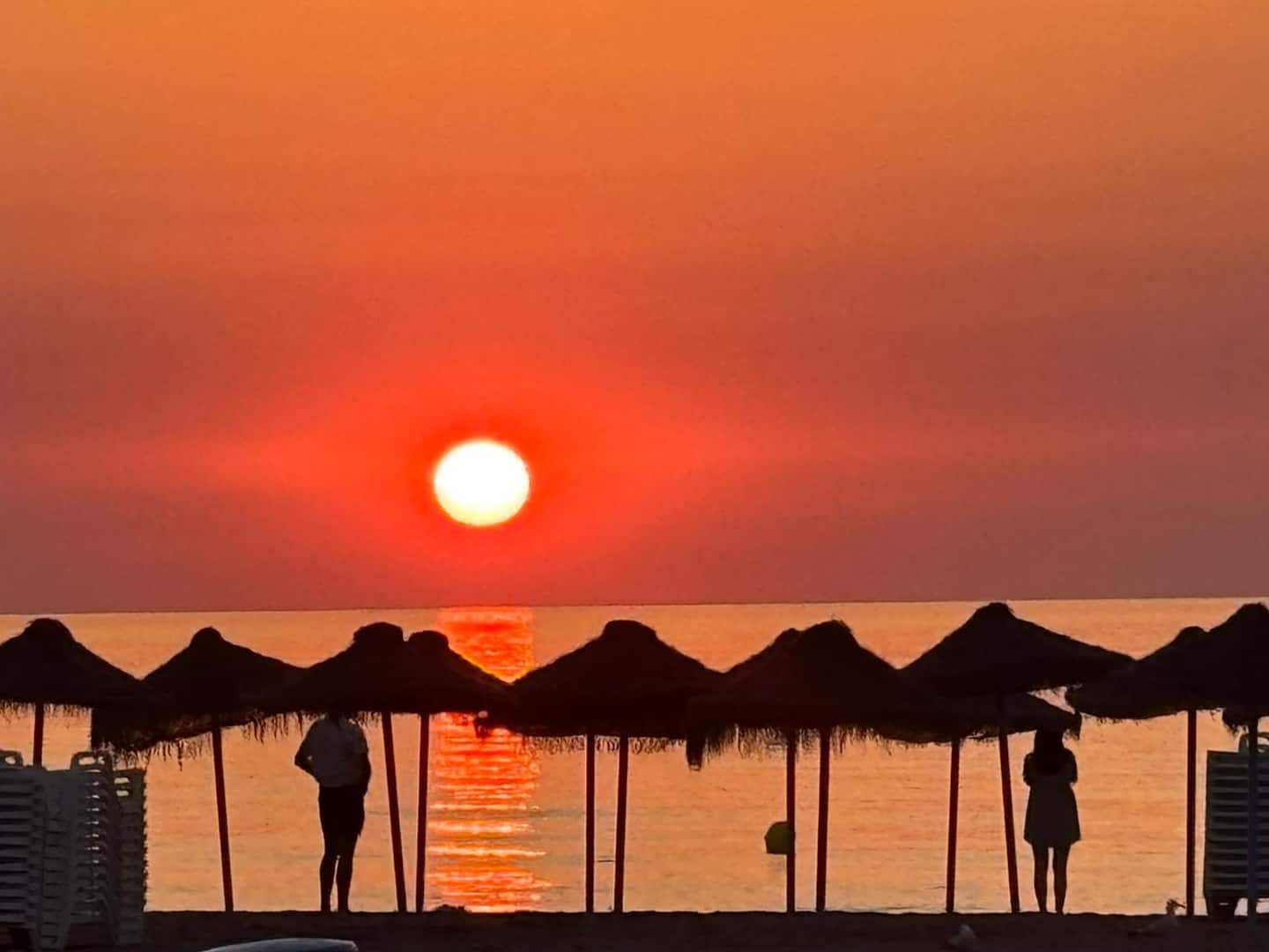 Straw umbrellas on Malvarrosa beach at sunrise